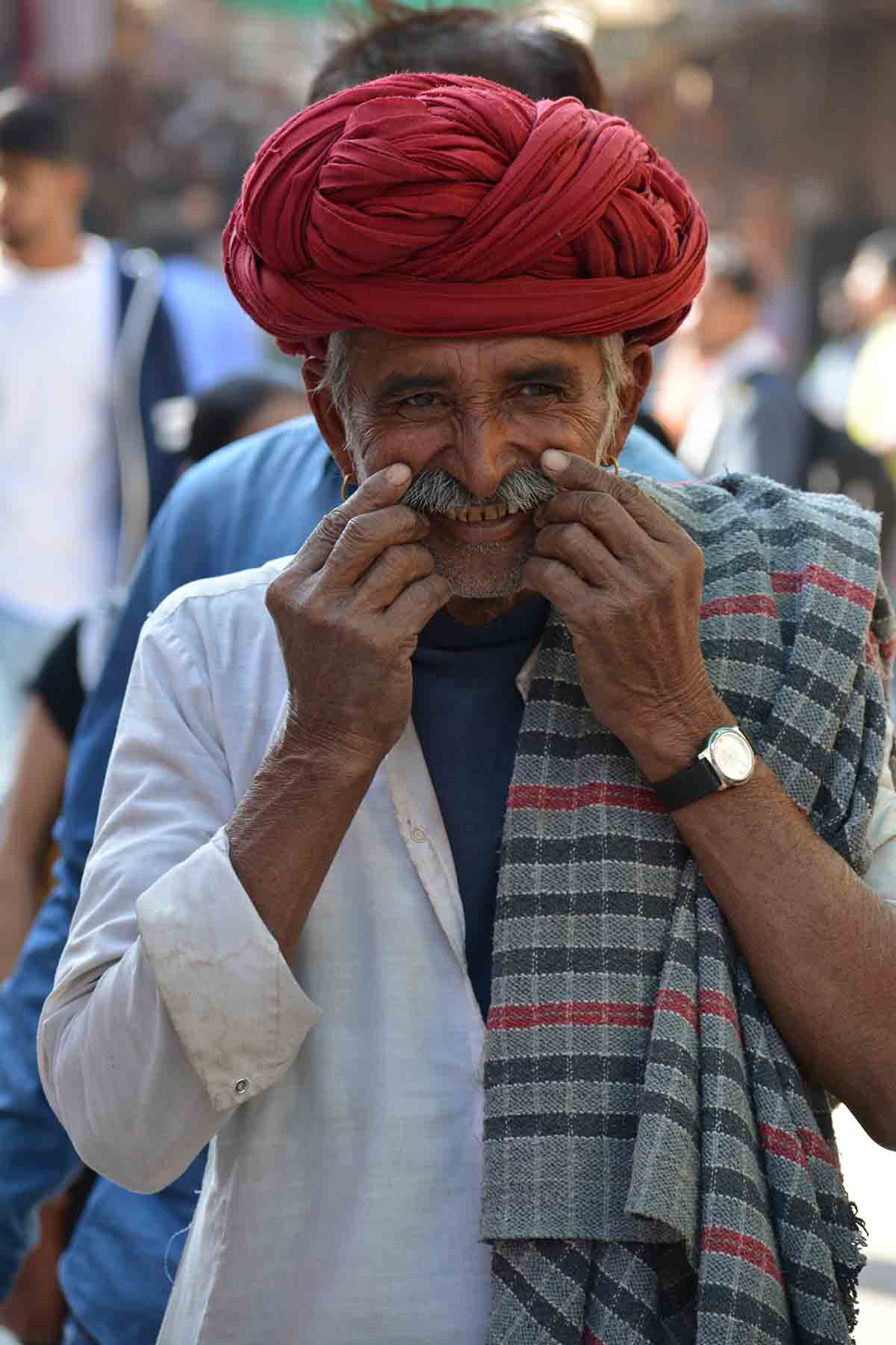 A happy Rajasthani man clad in traditional kurta- dhoti & bright coloured turban reflecting Rajasthani costume.