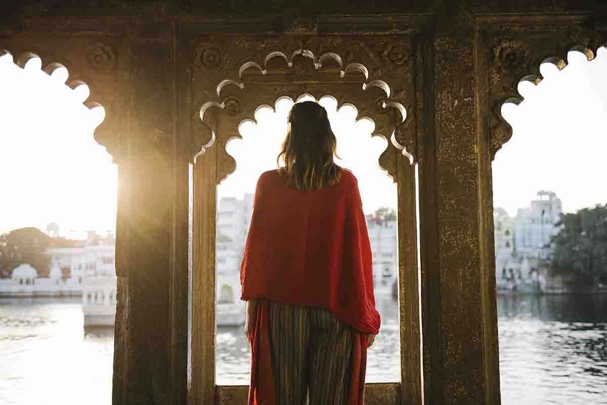 A lady in red absorbing the beauty of City Palace and lake Pichola in Udaipur