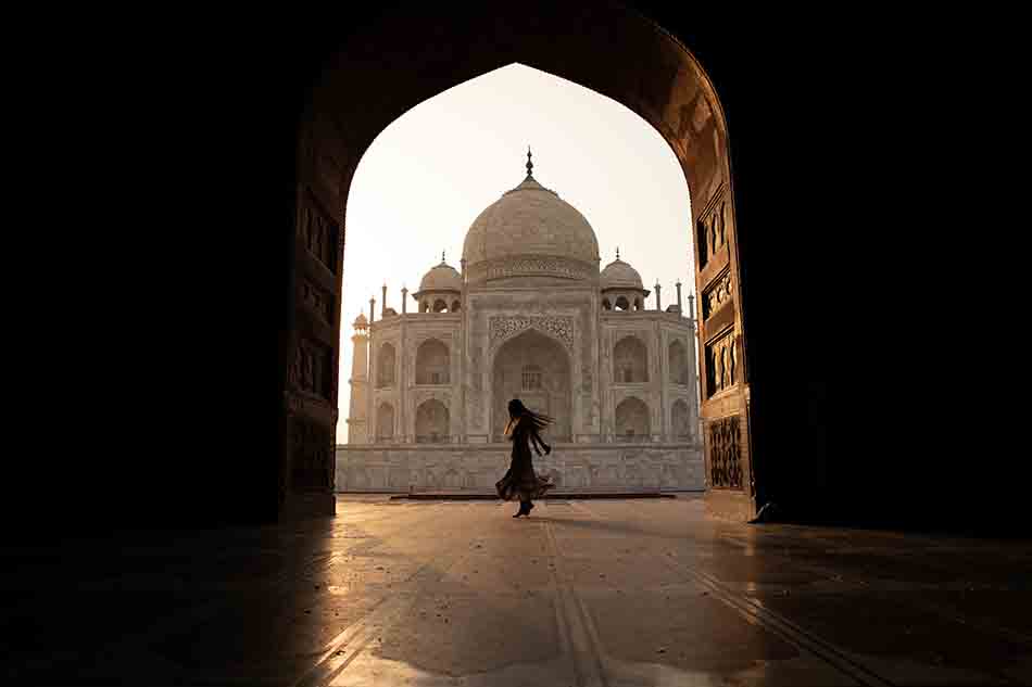 happy dance against he beauty of makrana white the Taj Mahal through the corridors