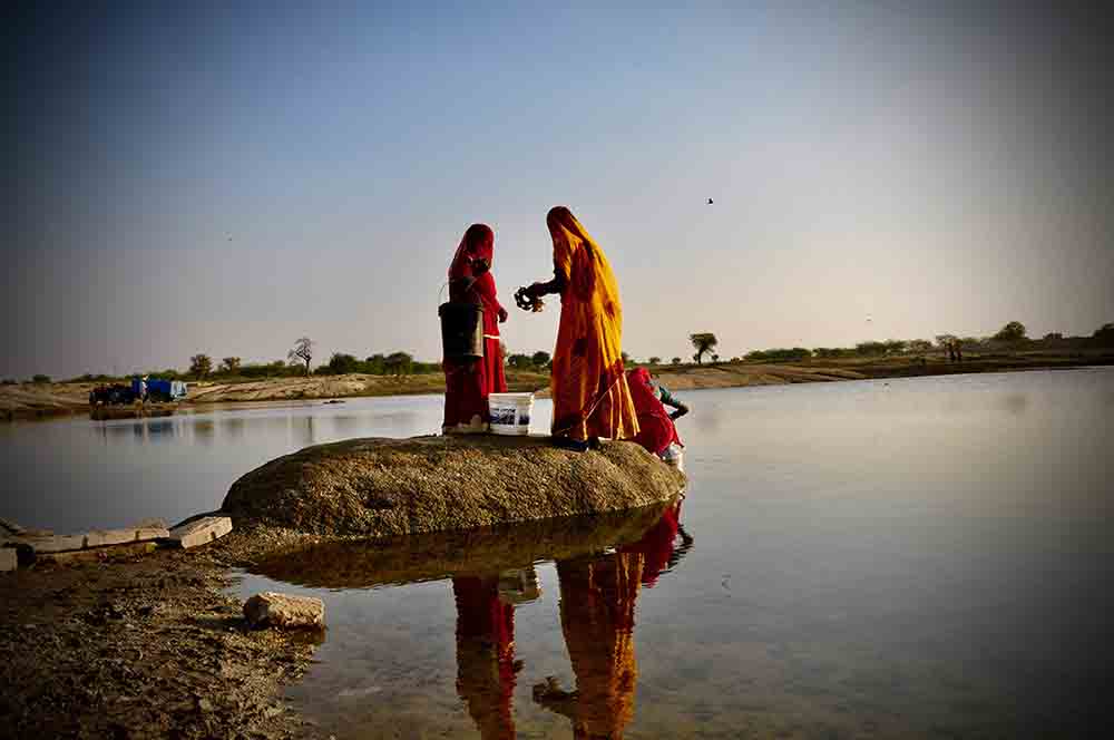 Typical Rajasthani women in villages of Rajasthan fetching water from natural lake I Dressed in bright clothes