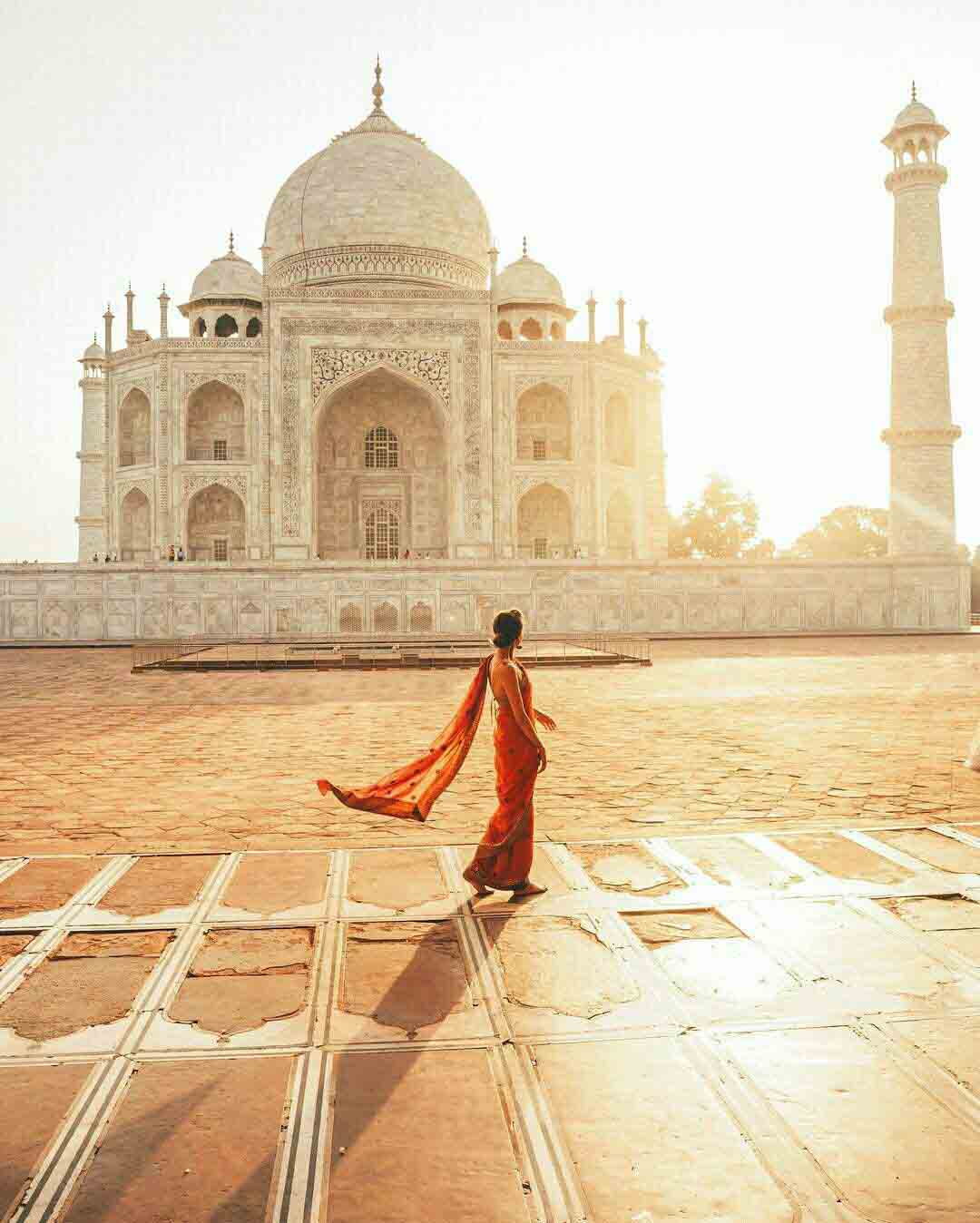 Foreign tourist clad in a bright Indian Saree in front of enchanting theTaj Mahal. Seven Wonders of the World.