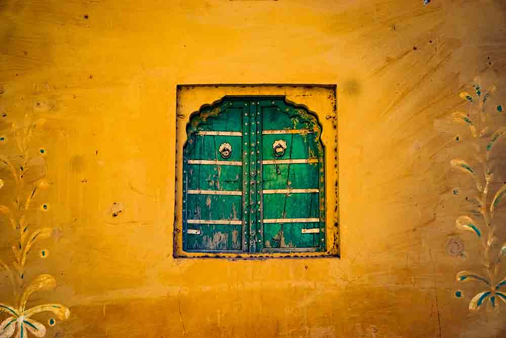 wooden jharokhas or windows in a village house of Rajasthan, walls decorated with mural arts and vibrant colours