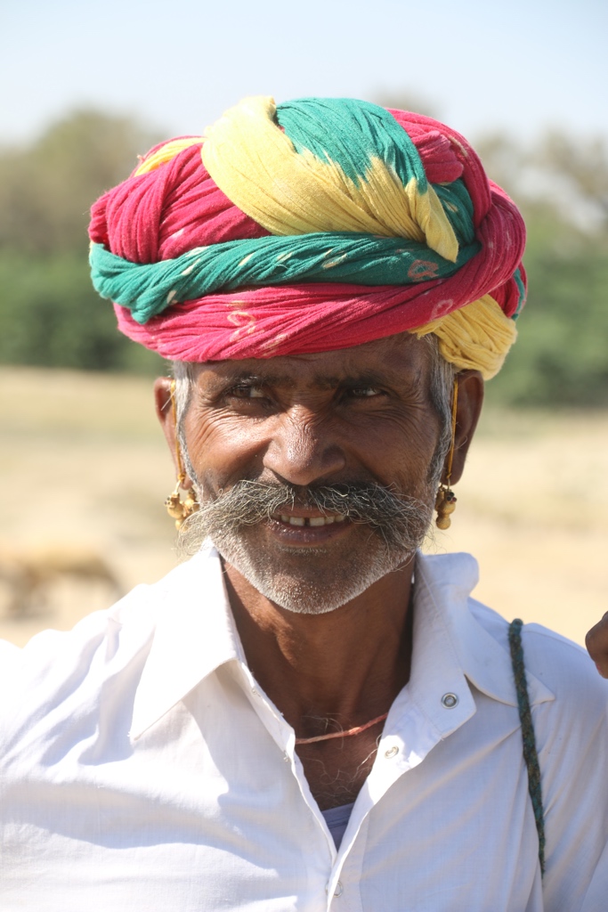 An old Rajasthani man with big moustaches wearing a colourful turban or pagri, flaunting his jewel pieces
